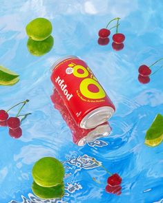 a soda can floating in the water surrounded by cherries