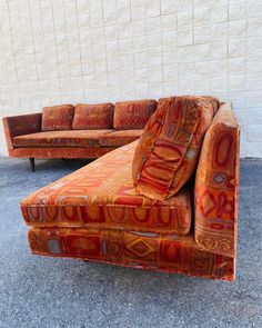 an orange couch and chair sitting next to each other in front of a white wall