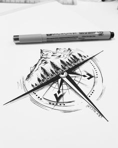 a pen is sitting on top of a piece of paper with a compass and mountains