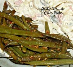 green beans with garlic and seasoning on a white plate next to some other food