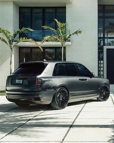 a silver car parked in front of a white building next to a palm tree on the sidewalk