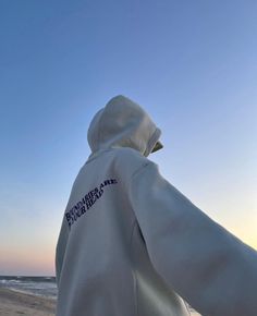 a person wearing a white hoodie on the beach