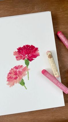 two pink flowers on a white paper with some crayons next to it and a marker