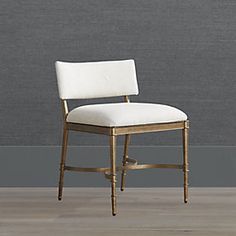 a white chair against a gray wall with wood trimmings and a beige upholstered seat