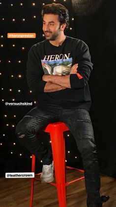 a man sitting on top of a red stool