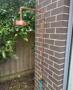 an outdoor shower head mounted to the side of a brick building