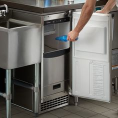 a man is opening the door to his stainless steel kitchen sink and dishwasher