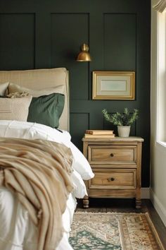 a bedroom with dark green walls and white bedding, gold framed pictures on the wall