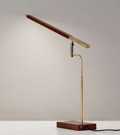 a desk lamp with a wooden base and a metal arm, on a white surface