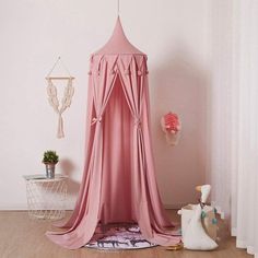 a pink canopy bed in the corner of a room