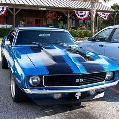 two muscle cars parked next to each other in a parking lot