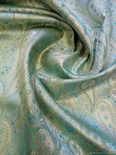 an image of a blue and green paisley pattern on a fabric textured with metallic foil