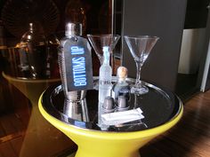 a yellow table topped with two martini glasses and bottles