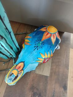 a blue and yellow fish statue sitting on top of a wooden floor