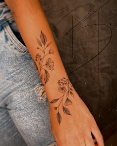 a woman's arm with flowers and leaves tattooed on the left side of her arm