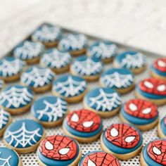 spiderman cookies are arranged in rows on a cookie sheet with white and blue icing