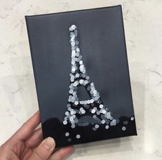 a hand holding up an acrylic painting with the eiffel tower on it