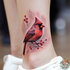 a red bird sitting on top of a tree branch with berries in it's legs