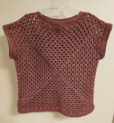 a crocheted top hanging on a hanger