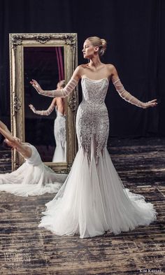 a woman in a white dress standing next to a mirror and holding her arms out