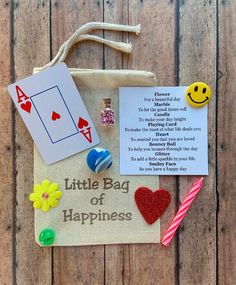 a little bag of happiness on a wooden table with some cards and pins attached to it