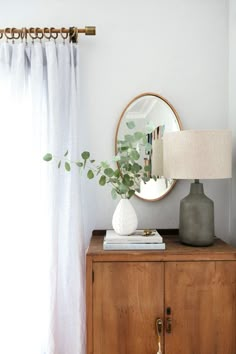 a wooden cabinet with a mirror and vase on top