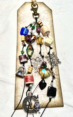 a necklace with many different charms hanging from it's side on a piece of wood