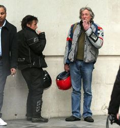 three men standing next to each other near a wall