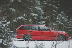 a red car is parked in the snow