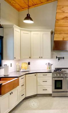 a kitchen with white cabinets and stainless steel stove top oven in the center of the room