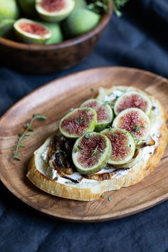 a wooden plate topped with sliced figs and bread