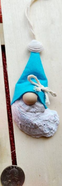 an ornament with a blue hat on top of a piece of wood next to a coin