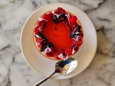 a dessert on a plate with a spoon next to it and a marble counter top