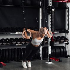 a woman is doing exercises in the gym with rings on her back and hands behind her head