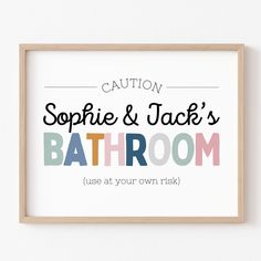 a bathroom sign hanging on the wall next to a wooden frame with words that say,'sophiie & jack's bathroom use at your own fish '