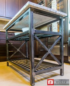 a kitchen island made out of metal and wood in the middle of a tile floor