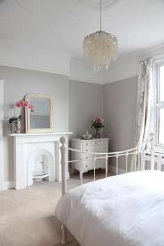 a white bed sitting next to a window with a chandelier hanging from the ceiling