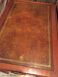 an old wooden table with writing on the top and gold trimming around the edges