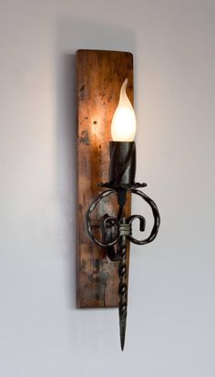 a wall light that is on the side of a wooden wall with a candle in it