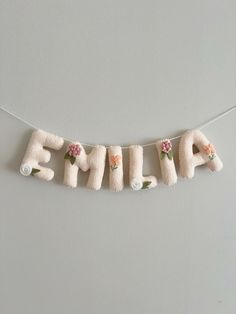 an embroidered name bunting with flowers and the word emla spelled in white letters