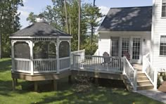 a white gazebo sitting on top of a lush green field next to a house