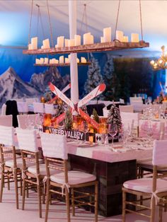 a dining table with candles and decorations on it in front of a snowy mountain backdrop