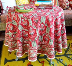 a table topped with books on top of a yellow rug next to a couch covered in pillows