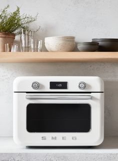 a white microwave oven sitting on top of a counter next to pots and pans