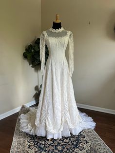 a white wedding dress on display in a room with a rug and potted plant