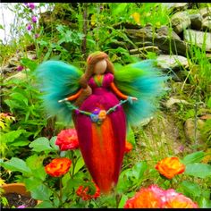 a fairy doll sitting on top of a flower pot in the middle of some flowers