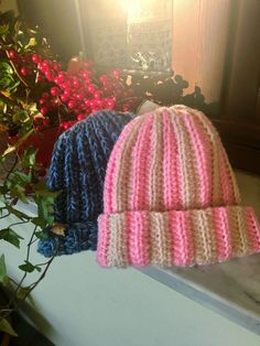 two knitted hats sitting next to each other on top of a window sill