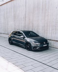 a grey car parked in front of a wall