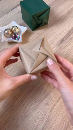 a person is holding an origami piece in their hand, next to some ornaments