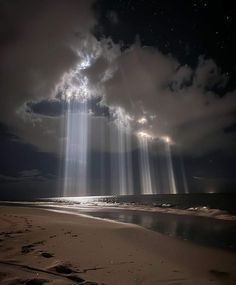 the sun shines brightly through clouds over an empty beach on a cloudy night with footprints in the sand